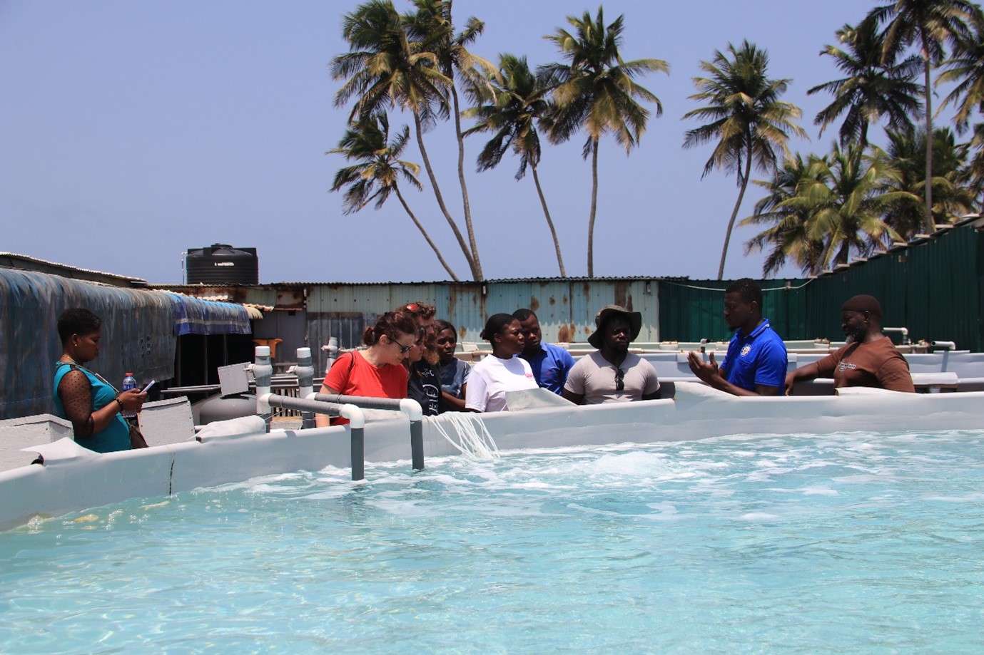 people standing around a large container filled with water, listening to someone who appears to be teaching