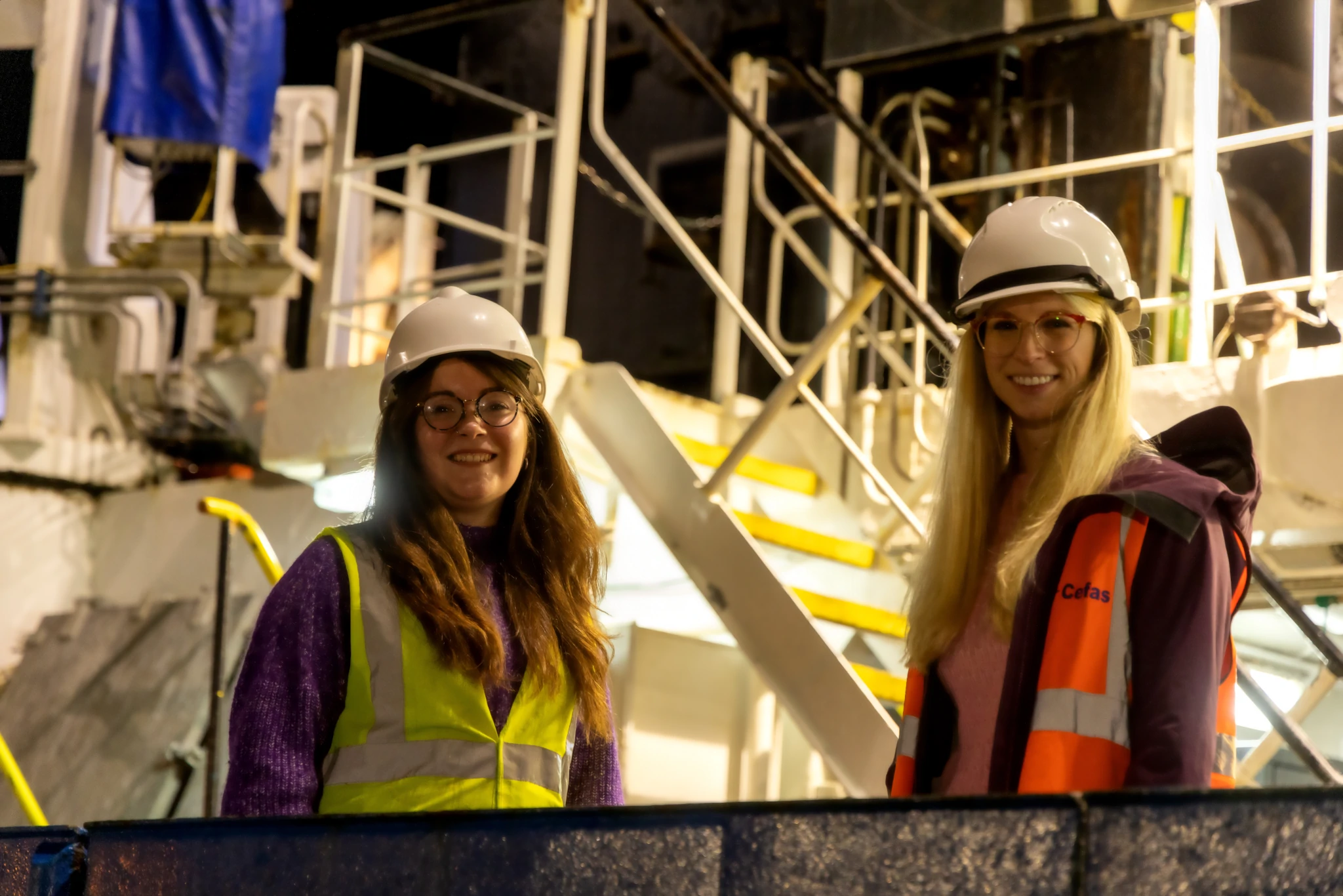 Two people stood on the deck of a ship at night