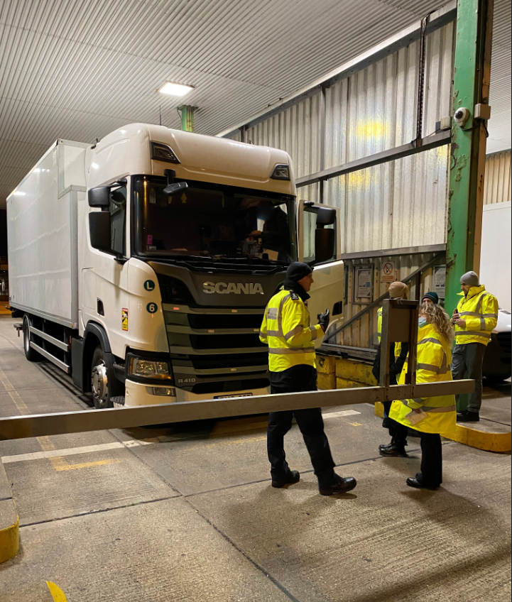 Enforcement officers standing by a lorry in a warehouse 