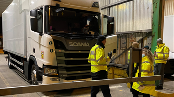 Enforcement officers standing by a lorry in a warehouse 