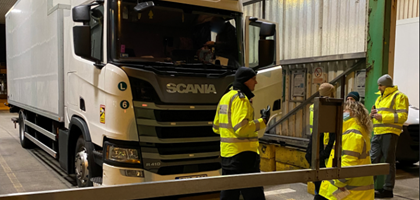 Enforcement officers standing by a lorry in a warehouse 