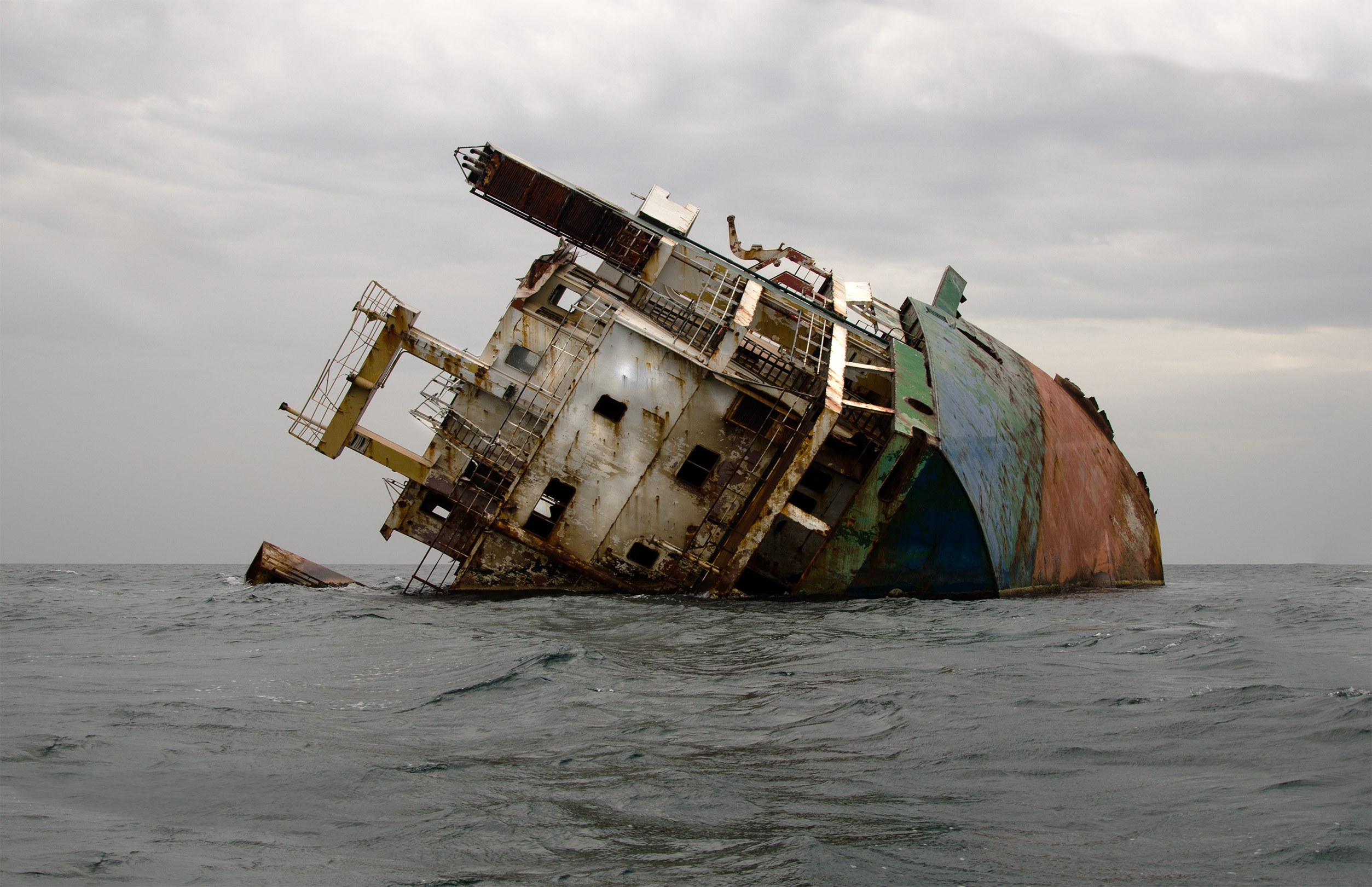 A ship wreck in the ocean, lopsided and starting to rust 