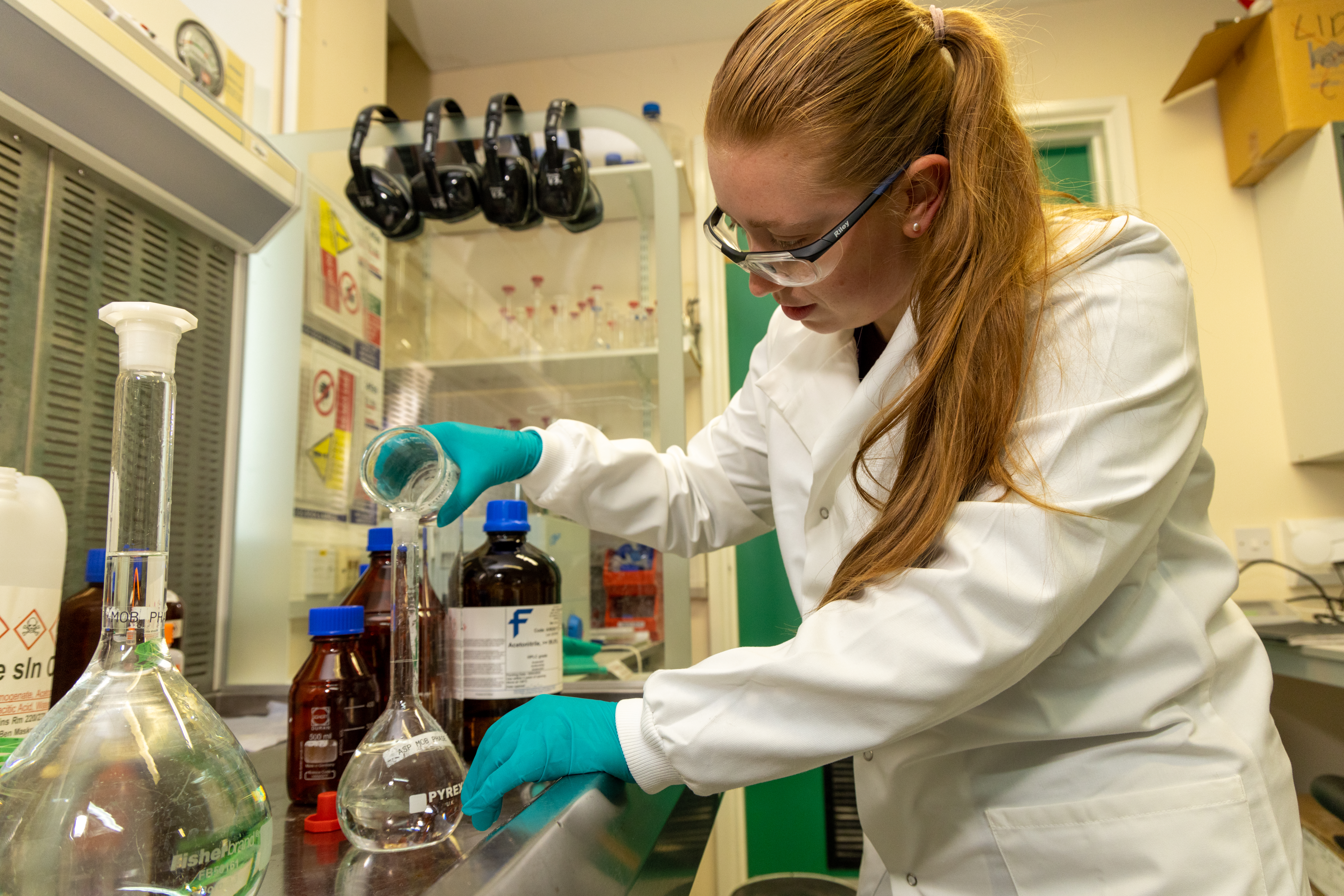 a person pouring liquid from a beaker in a lab