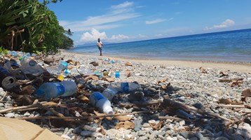 man walking on beach with plastic litter