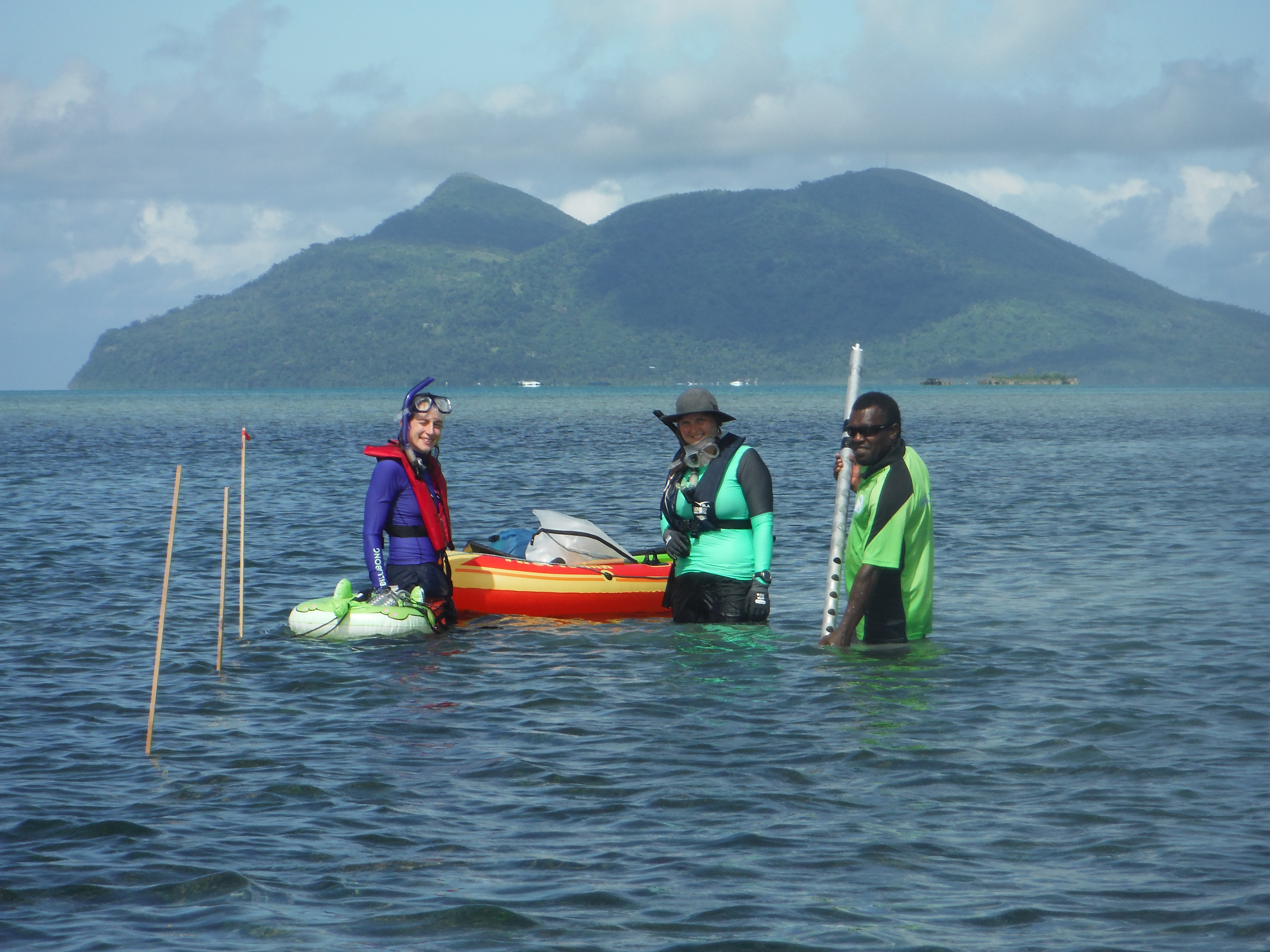 three scientists standing in the sea deploying scientific equipment