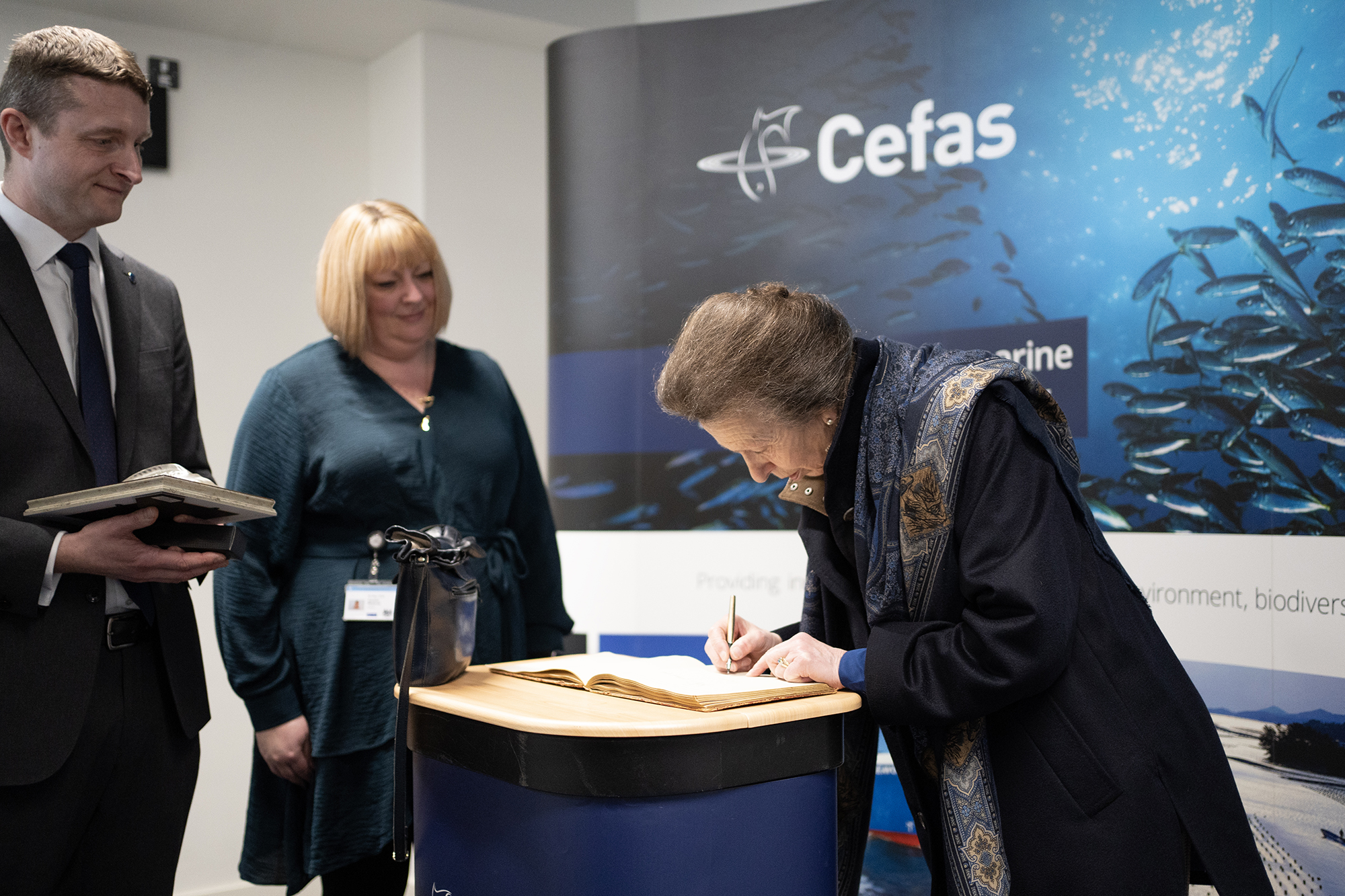 The Princess Royal signing the visitor book next to next to her father’s signature, HRH The late Duke of Edinburgh, who visited the Lowestoft Laboratory in 1956