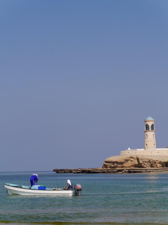 a boat at sea with a lighthouse in the background