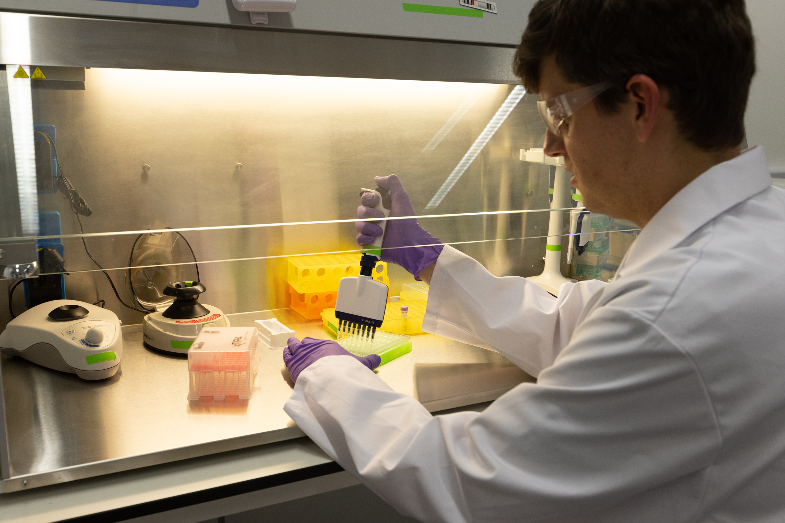 Wastewater surveillance lab with person working at a fume cupboard using a pipete