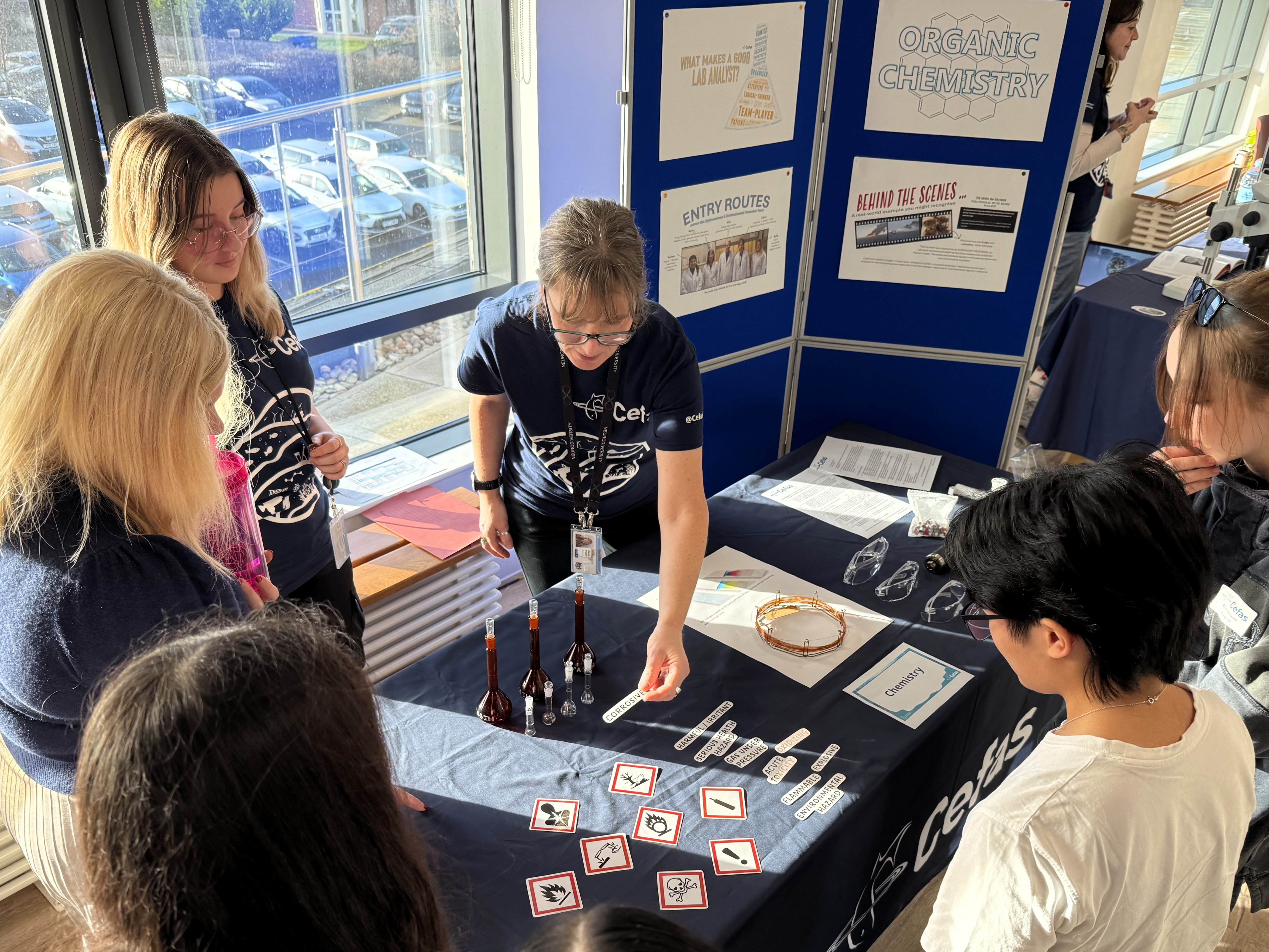 Cefas staff holding information with chemistry equipment on table in front of them