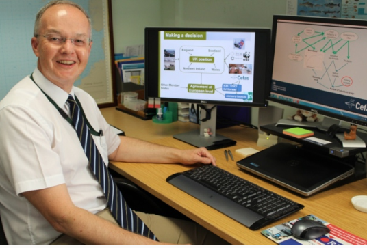 Picture of man sat in front of computer screens