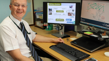 Picture of man sat in front of computer screens