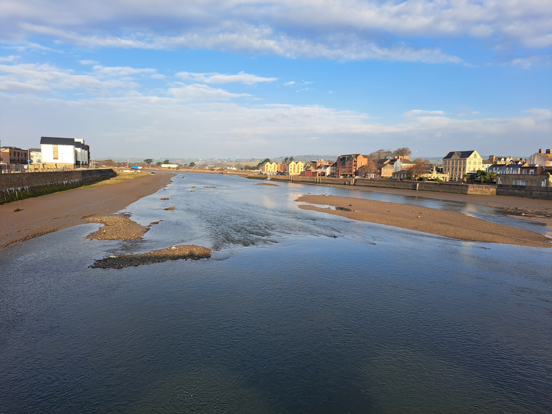 a river estuary at low tide with sandbanks and houses on either side
