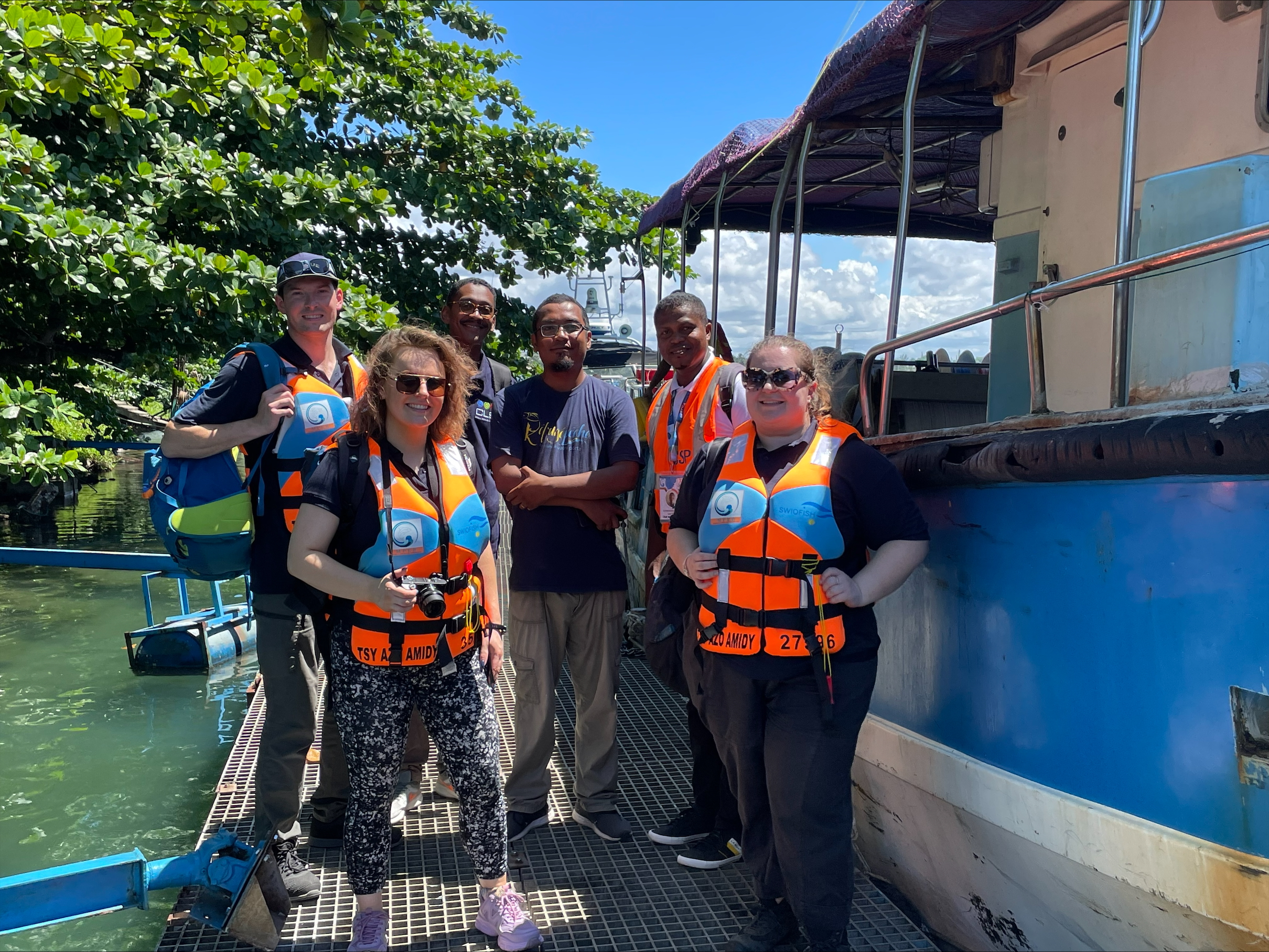 a group of people wearing lifejackets standing alongside a vessel ready to get to work