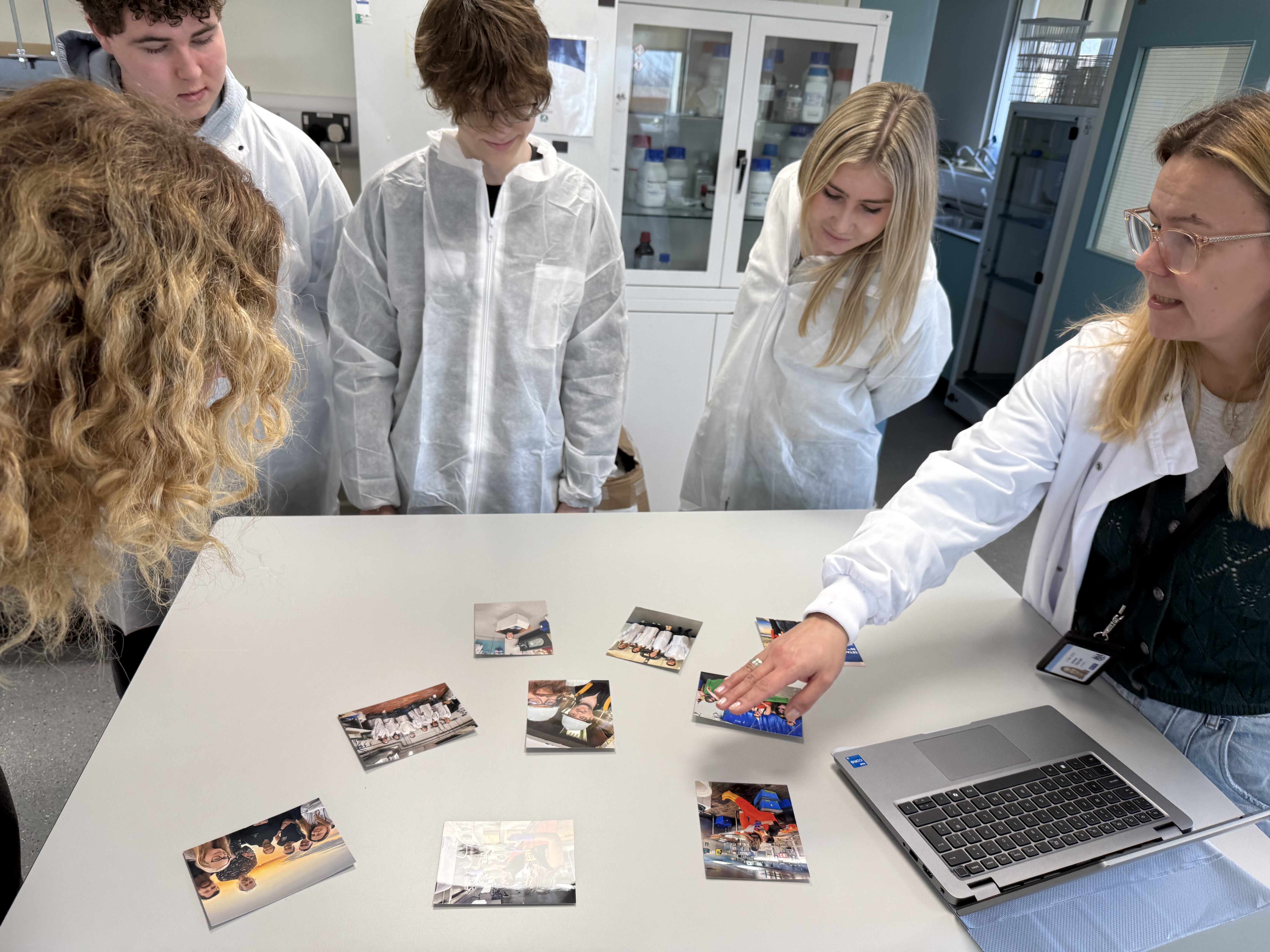 Students in lab coats looking at information on table in laboratory